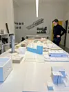 Person ser ned på mange arkitekturmodeller på bord i lyst kontor