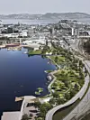 Illustrasjon av moderne havnepark med vann, grønne områder og bybebyggelse i bakgrunnen