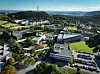 Dronebilde som viser campus med bygninger, grøntarealer og parkeringsplass i landlig landskap.