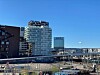 Moderne bygninger ved vannet med bro, gjerder og klar blå himmel.