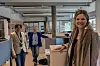 Tre personer står i et lyst kontor med åpne arbeidsplasser og møterom i bakgrunnen.