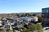 Bylandskap med boligområder, kontorbygg og en kran mot blå himmel.