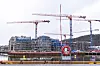 Boligblokker under bygging i Bjørvika i Oslo med flere røde kraner og vann i forgrunnen.