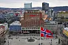 Panoramautsikt over Youngstorget i Oslo med bygårder, torg og norsk flagg i forgrunnen.