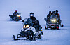 Jonas Gahr Støre kjører snøscooter foran flere andre snøscootere på snøfelt ved Longyearbyen.