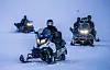 Jonas Gahr Støre kjører snøscooter foran flere andre snøscootere på snøfelt ved Longyearbyen.