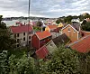 Utsikt over røde tak og hus på Innlandet i Kristiansund med havn og skyet himmel i bakgrunnen.