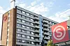 Studentboligbygg på Kringsjå i Oslo med stor rød logo på fasaden under blå himmel.