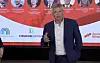 Bjørnar Skjæran taler foran en konferansevegg med portretter og logoen til Eiendom Norge.