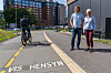 To personer ved en urban gate mens en syklist passerer i et merket sykkelfelt.