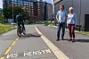To personer ved en urban gate mens en syklist passerer i et merket sykkelfelt.