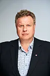 Portrett av Brigt Olav Samdal i mørk dressjakke mot en lys, nøytral bakgrunn.