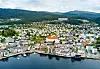 Luftpanorama over Molde med by, havn, fjord og grønne åser.