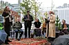 Personer deltar i en utendørs samtale foran et urbant bylandskap.