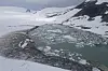 Isflak i et smeltevannsbasseng omgitt av snødekte fjellsider ved Harbardsbreen.