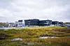 Kirkenes sykehus ligger bak et myrlandskap ved Andrevann under en overskyet himmel.